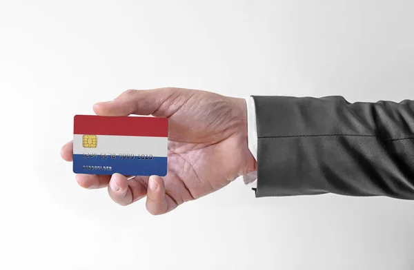 Bankovní kreditní plastová karta s vlajkou Nizozemska držící muže v elegantním obleku — Stock fotografie