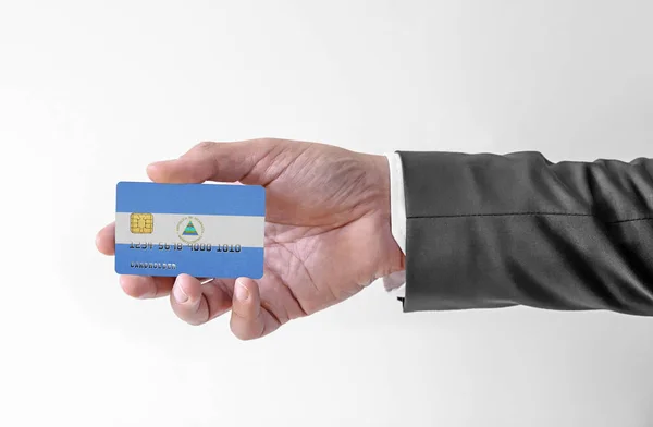 Bankovní kreditní plastová karta s vlajkou Nikaraguy držící muže v elegantním obleku — Stock fotografie