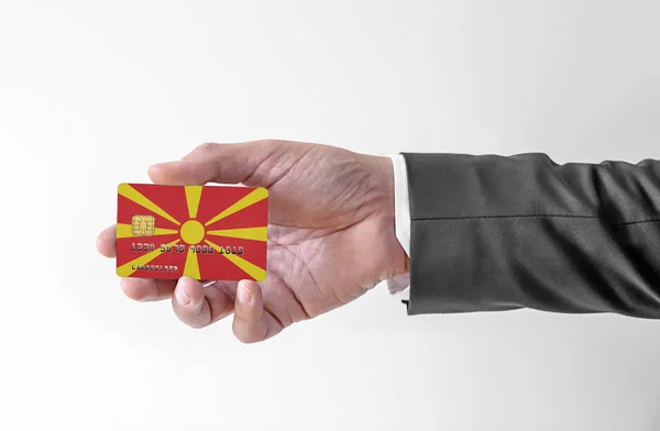 Banco tarjeta de crédito de plástico con la bandera de Macedonia del Norte la celebración del hombre en traje elegante — Foto de Stock