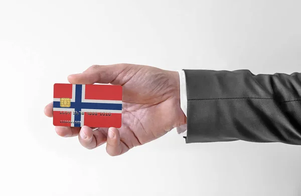 Bankovní kreditní plastová karta s vlajkou Norska drží muže v elegantním obleku — Stock fotografie