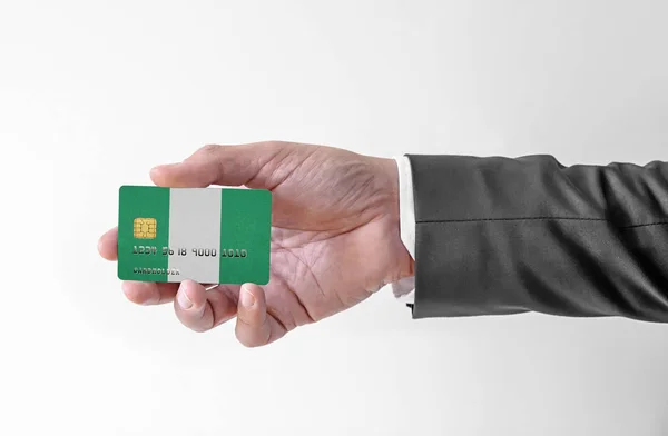 Банковская кредитная пластиковая карта с флагом Нигерии, держащая человека в элегантном костюме — стоковое фото