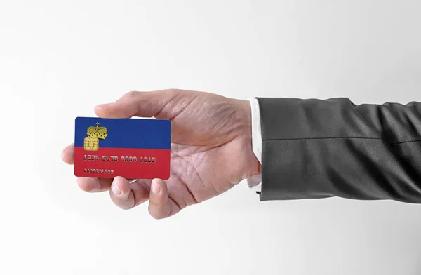 Bankovní kreditní plastová karta s vlajkou Lichtenštejnska držící muže v elegantním obleku — Stock fotografie