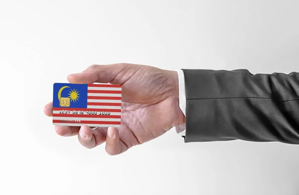 Bank credit plastic card with flag of Malaysia holding man in elegant suit — 스톡 사진