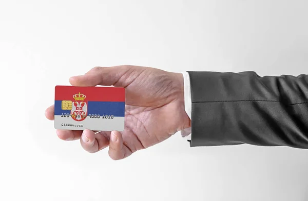 Banco tarjeta de crédito de plástico con la bandera de Serbia la celebración del hombre en traje elegante —  Fotos de Stock