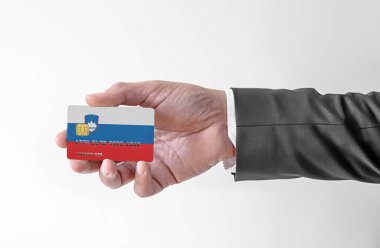 Bank credit plastic card with flag of Slovenia holding man in elegant suit 