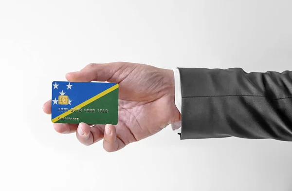 Bankovní kreditní plastová karta s vlajkou Šalamounových ostrovů držící muže v elegantním obleku — Stock fotografie