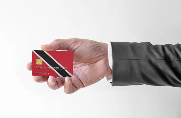 Bankovní kreditní plastová karta s vlajkou Trinidad a Tobago držení muž v elegantním obleku — Stock fotografie