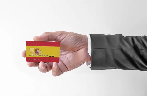 Bankovní kreditní plastová karta s vlajkou Španělska drží muže v elegantním obleku — Stock fotografie
