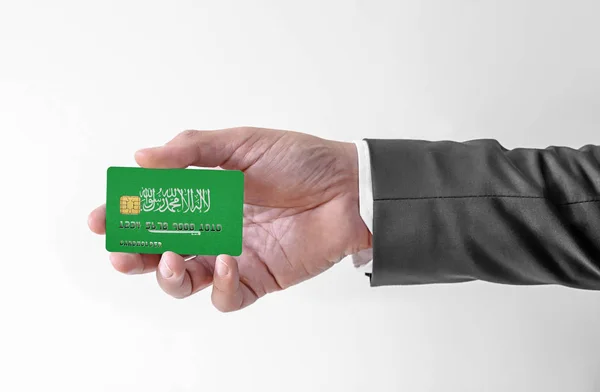 Karta kredytowa banku z flagą Arabii Saudyjskiej posiadacz człowieka w eleganckim garniturze — Zdjęcie stockowe