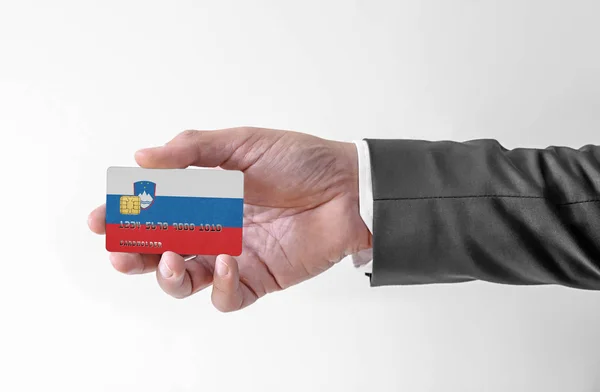 Банковская кредитная пластиковая карта с флагом Словении, держащая человека в элегантном костюме — стоковое фото