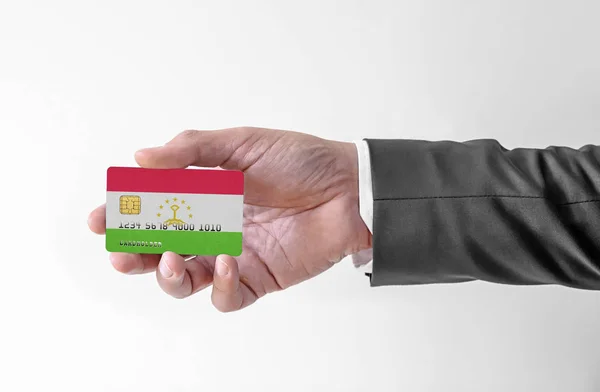Bankovní kreditní plastová karta s vlajkou Tádžikistánu drží muže v elegantním obleku — Stock fotografie