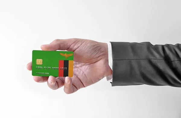 Bankovní kreditní plastová karta s vlajkou Zambie držení muž v elegantním obleku — Stock fotografie
