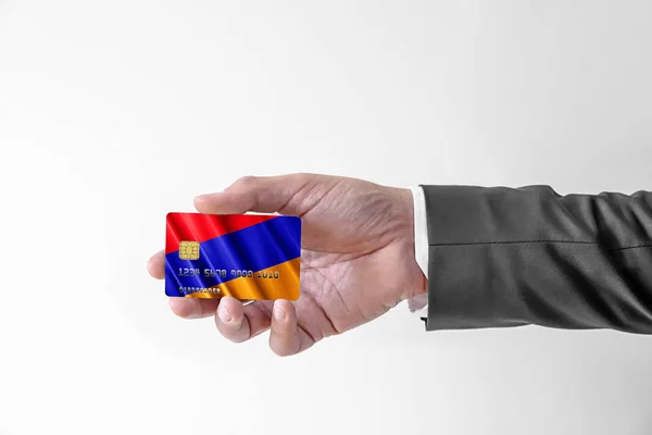 Homem em elegante terno personalizado segurando cartão de crédito bancário de plástico com bandeira da Armênia — Fotografia de Stock