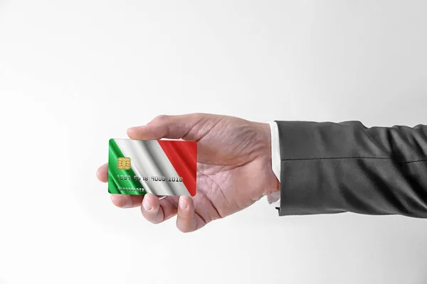 Man in elegant custom suit holding bank credit plastic card with flag of Italy