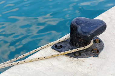 Tekne için beton rıhtımda eski siyah demir kazık. 