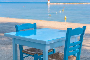 Yunanistan 'da deniz altyapısı olan tipik bir meyhanede mavi masa ve sandalyeler