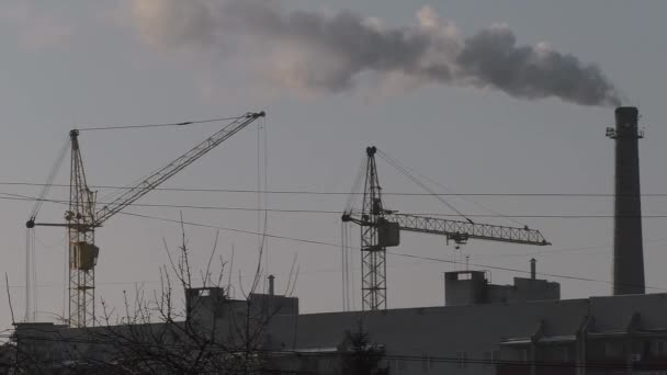 Two tower cranes are working against the gray sky — Stock Video