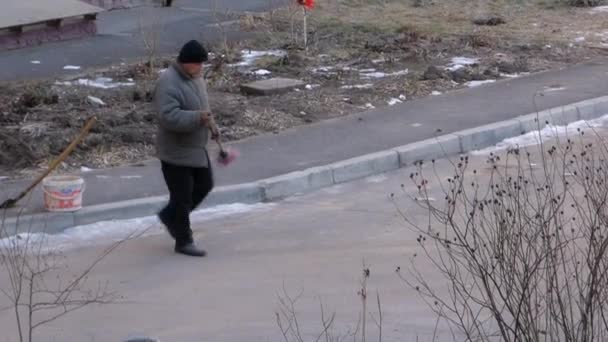 Janitor with red broom sweeping the street — Stock Video