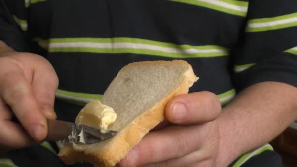 El hombre extiende mantequilla sobre el pan — Vídeo de stock
