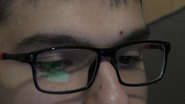 Joven con gafas mira de cerca el monitor — Vídeos de Stock