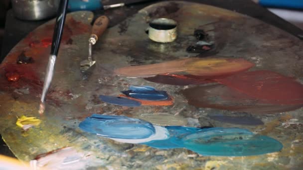 Painting with oil paints with a palette. Close-up of oil paint on the palette. The process of creating oil painting — Stock Video