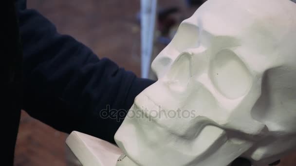 Dibujando un cráneo humano. El artista dibuja un boceto de un cráneo humano, de la vida. Cráneo de yeso y arte . — Vídeo de stock