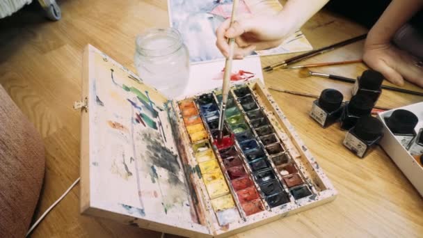 La chica dibuja una paleta de pinturas de acuarela. El proceso de creación de una pintura de acuarela. Acuarela y creatividad — Vídeos de Stock