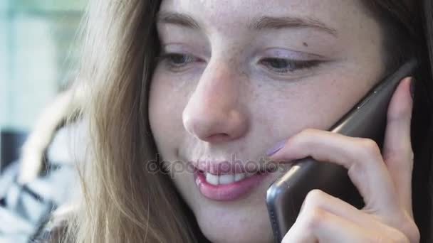 La chica sonriente europea hablando por teléfono. Conversación positiva de una chica en el teléfono. Comunicación moderna y redes sociales — Vídeo de stock