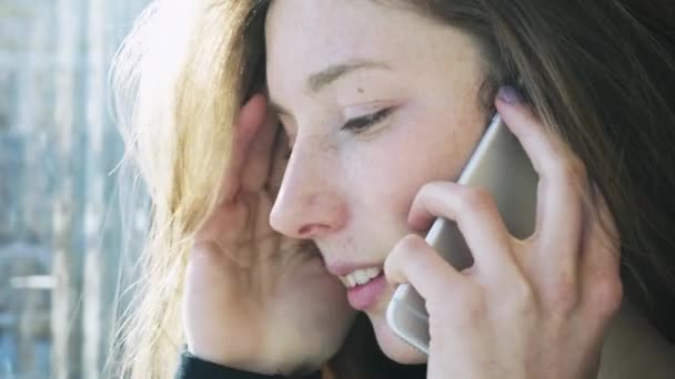 La chica sonriente europea hablando por teléfono. Conversación positiva de una chica en el teléfono. Comunicación moderna y redes sociales — Vídeos de Stock