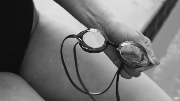 swimming goggles in the hands of the swimmer. Sports accessories for swimmers. Swimmers at the Olympics