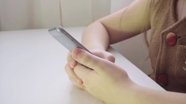 Petite menina europeia goza de um smartphone. Close-up do telefone nas mãos das crianças — Vídeo de Stock