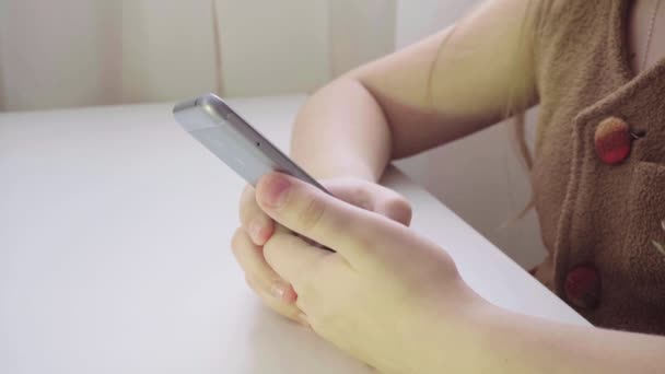 小柄なヨーロッパの女の子は、スマート フォンを楽しんでいます。電話での子供たちの手のクローズ アップ — ストック動画