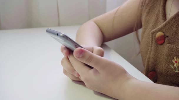 Petite ragazza europea gode di uno smartphone. Primo piano del telefono tra le mani dei bambini — Video Stock