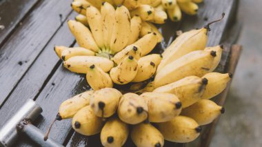 bir sürü olgun muz bir ahşap masa yakın çekim üstten görünüm üzerinde yalan. Tropikal meyve ve yolculukta Bapu diyet. Asya'nın tropikal meyveler