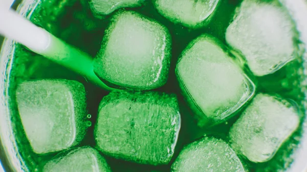 Close-up de um refrigerante com cubos de gelo em um copo. Bebida fresca com gelo de cor verde — Fotografia de Stock