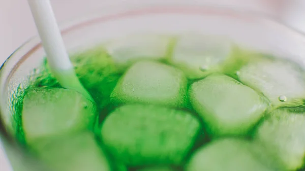 Gros plan d'un soda avec des cubes de glace dans un verre. Boisson fraîche avec glace de couleur verte — Photo