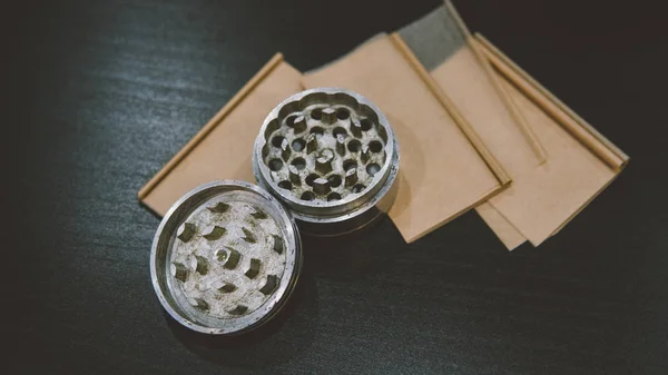 Metallic silver grinder for buds of marijuana  lying on smoke papers close-up. Legalize concept — Stock Photo, Image