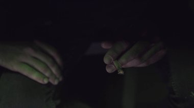 genç bir adam haddelenmiş jointer yeşil ışık yakın çekim içinde içinde esrar tomurcukları Sigara.