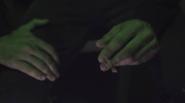 genç bir adam haddelenmiş jointer yeşil ışık yakın çekim içinde içinde esrar tomurcukları Sigara.