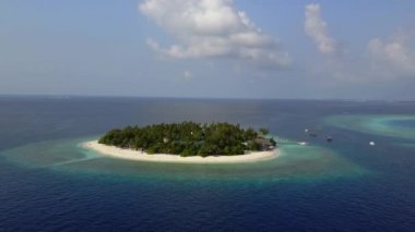 Kamera uzak beyaz kum palmiye ağaçları ve Maldivler üzerinde turkuaz Hint okyanusu ile yuvarlak tropikal atoll island resort otelden hareket eder, 4k yukarıdan drone görüntüleri havadan görünümü