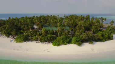 Kamera uzak beyaz kum palmiye ağaçları ve Maldivler üzerinde turkuaz Hint okyanusu ile yuvarlak tropikal atoll island resort otelden hareket eder, 4k yukarıdan drone görüntüleri havadan görünümü