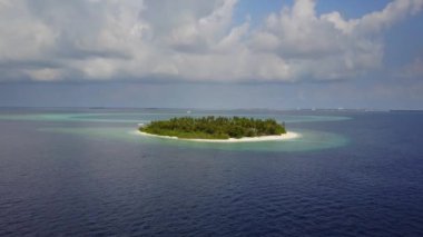 Kamera uzak beyaz kum palmiye ağaçları ve Maldivler üzerinde turkuaz Hint okyanusu ile yuvarlak tropikal atoll island resort otelden hareket eder, 4k yukarıdan drone görüntüleri havadan görünümü