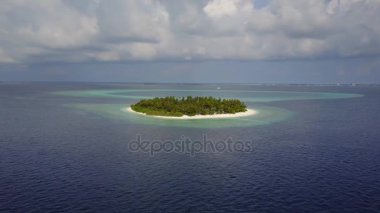 Kameranın küçük yuvarlak tropikal atoll Island resort hotel beyaz kum palmiye ağaçları ve turkuaz Hint Okyanusu ile çevresinde Maldivler, dron görüntüleri havadan görünümü yukarıdaki 4 k uçar