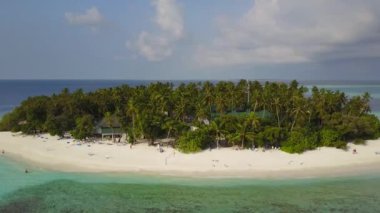 Kameranın küçük yuvarlak tropikal atoll Island resort hotel beyaz kum palmiye ağaçları ve turkuaz Hint Okyanusu ile çevresinde Maldivler, dron görüntüleri havadan görünümü yukarıdaki 4 k uçar