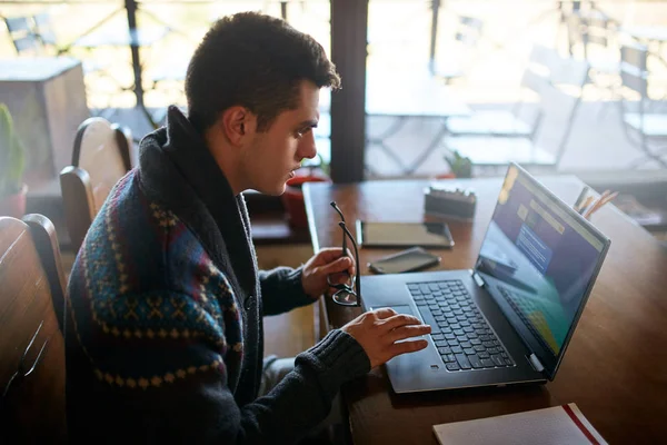 Uomo d'affari che lavora con documenti e tablet portatili e smartphone in ufficio. Freelancer navigazione web in caffè. Bello hipster in maglia maglione che tiene gli occhiali in mano agli occhi riposo . — Foto Stock