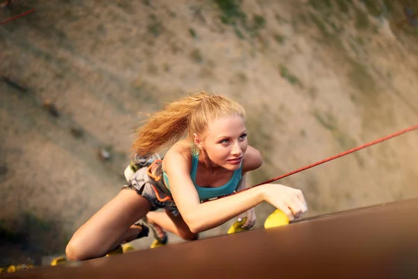 Starke Frau und unternehmerisches Erfolgskonzept. Draufsicht auf junge kaukasische hübsche Frau übt Klettern auf künstlichen Felswänden im Freien. schlanke sportliche Blondine beim Speed-Bouldern. — Stockfoto