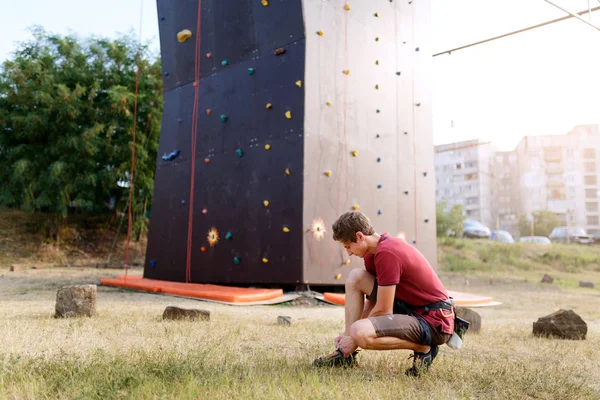 Mann schnürt vor Klettertraining orangefarbene Schuhe und Schnürsenkel. — Stockfoto