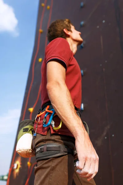 Detailaufnahme eines Bergsteigers mit Sicherheitsgurt und Kletterausrüstung im Freien mit Kreide-Magnesium-Tasche und Karabiner. künstliche Trainingskletterwand im Hintergrund. Mann bereitet sich auf Training vor — Stockfoto