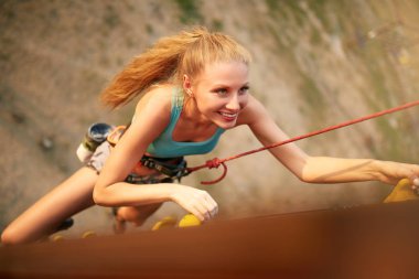 Güçlü kadın ve iş başarı kavramı. Üstten Görünüm genç beyaz güzel kadının yapay kaya duvar açık havada üzerinde tırmanma pratik. Hız bouldering oturum eğitim ince sportif sarışın.