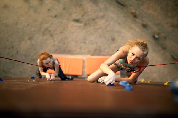 Mulher forte e conceito de negócio. Vista superior de dois jovens alpinistas que se aproximam do ponto de chegada na pista de velocidade das competições de escalada ao ar livre na parede de rocha artificial . — Fotografia de Stock